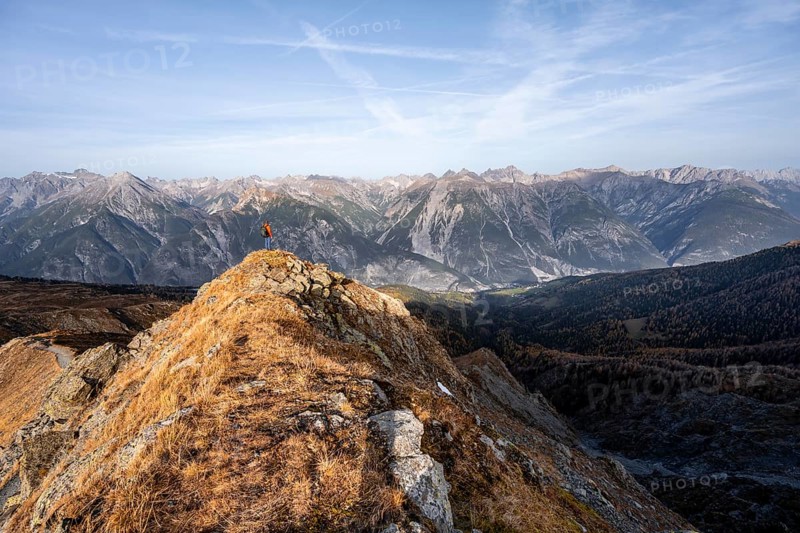 Mountaineer on the ridge in front of a mountain panorama, view from the ridge of the Venet to mountains of the Parzinn group in the Lechtal Alps, yellow larches in autumn, Venet crossing, Ötztal Alps, Tyrol, Austria, Europe