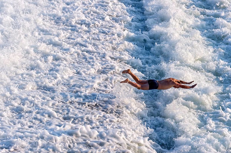 Man bathing in the spray of the Lech weir, jumping into the white foaming water of the cascades, river Lech, Landsberg am Lech, Upper Bavaria, Bavaria, Germany, Europe