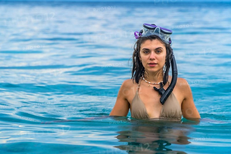 Young woman wearing snorkeling gear, swimming in the crystal clear waters of white beach, moalboal, on the island of cebu, philippines
