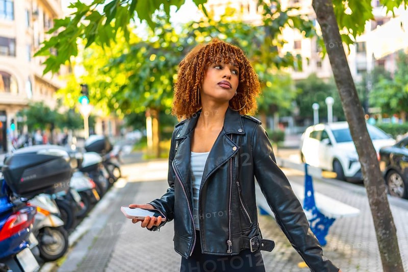 Side view of a beauty millennial latin woman listening to music walking along a city