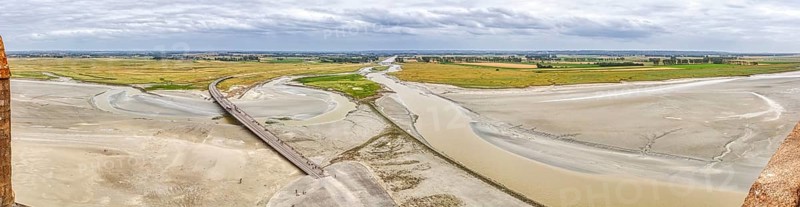 Extensive river landscape with sandbanks and green meadows under a cloudy sky, Le Mont-Saint-Michel