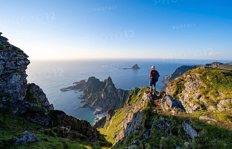 Mountaineer on the summit of Måtind or Måtinden, view of picturesque coastal landscape, rocky coast and sea, Andøya Island, Vesterålen, Nordland, Norway, Europe