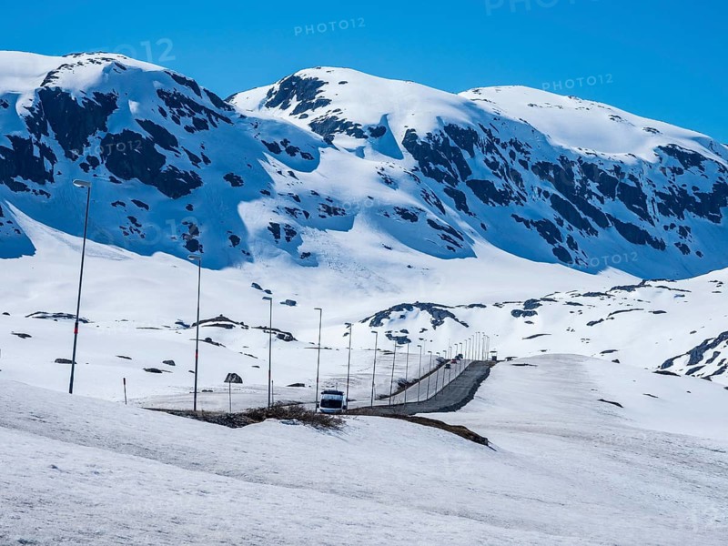 Camper van driving through snowy high mountain landscape, Haukelivegen road, E134, Norway, Europe