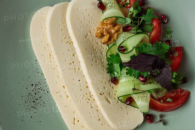 Sliced Imeruli cheese, Georgian cheese, with vegetables, top view, no people