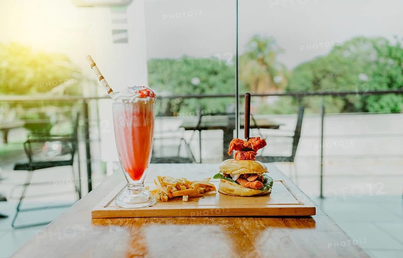 Delicious chicken burger with french fries and strawberry milkshake on restaurant table. Hamburger with french fries and strawberry milkshake on wooden table isolated
