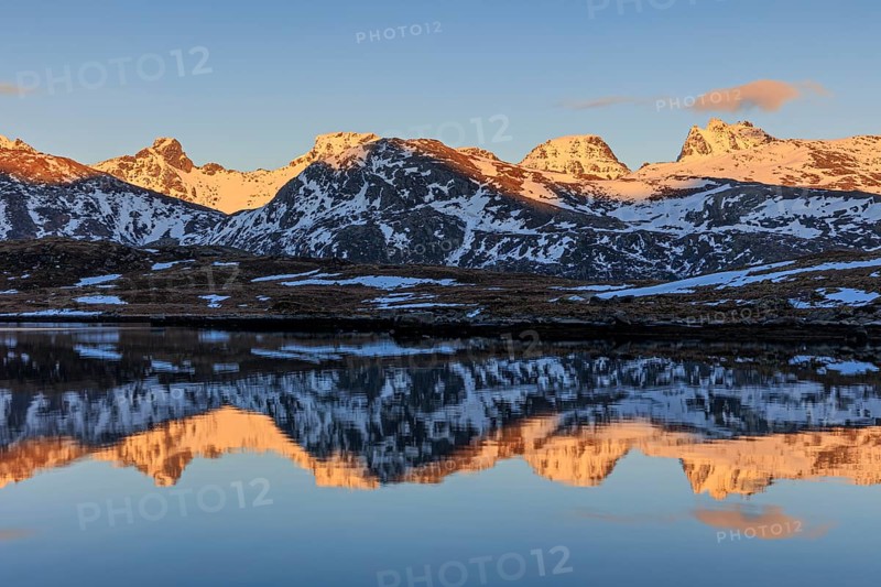 Steep mountains reflected in fjord, evening light, snowy, winter, Moskenesoya, Lofoten, Norway, Europe