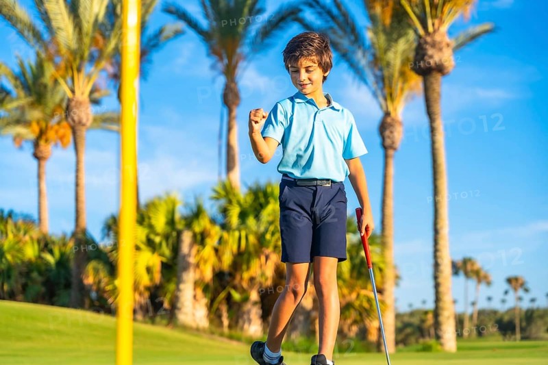 Child celebrating with fist that he makes a put in a green golf course