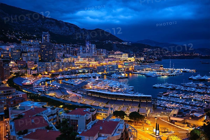 Aerial view of Monaco Monte Carlo harbour and illuminated city skyline in the evening blue hour twilight. Monaco Port night view with luxurious yachts