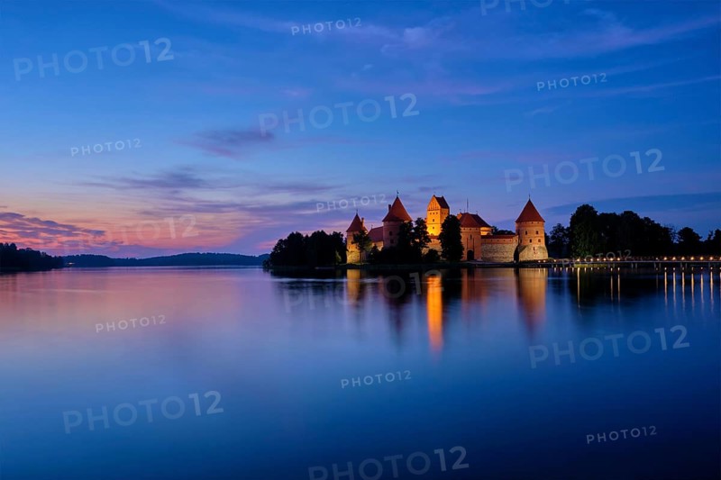 Trakai Island Castle in lake Galve illuminated in twilight reflecting in peaceful water, Lithuania, Europe