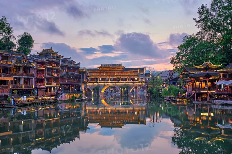 Chinese tourist attraction destination, Feng Huang Ancient Town (Phoenix Ancient Town) on Tuo Jiang River illuminated at night. Hunan Province, China, Asia