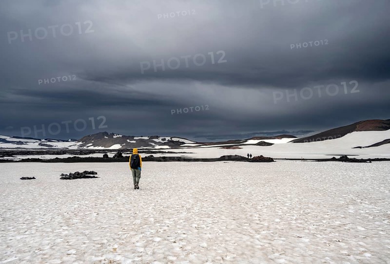 Hikers in snow-covered volcanic landscape with volcanic sand and petrified lava, crater of Askja volcano, Icelandic highlands, Iceland, Europe