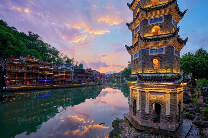 Chinese tourist attraction destination, Feng Huang Ancient Town (Phoenix Ancient Town) on Tuo Jiang River with Wanming Pagoda illuminated at night. Hunan Province, China, Asia