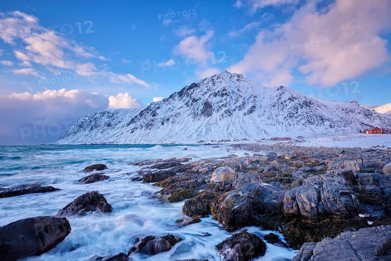 Beach of Norwegian sea on rocky coast in fjord on sunset in winter. Vareid beach, Lofoten islands, Norway, Europe