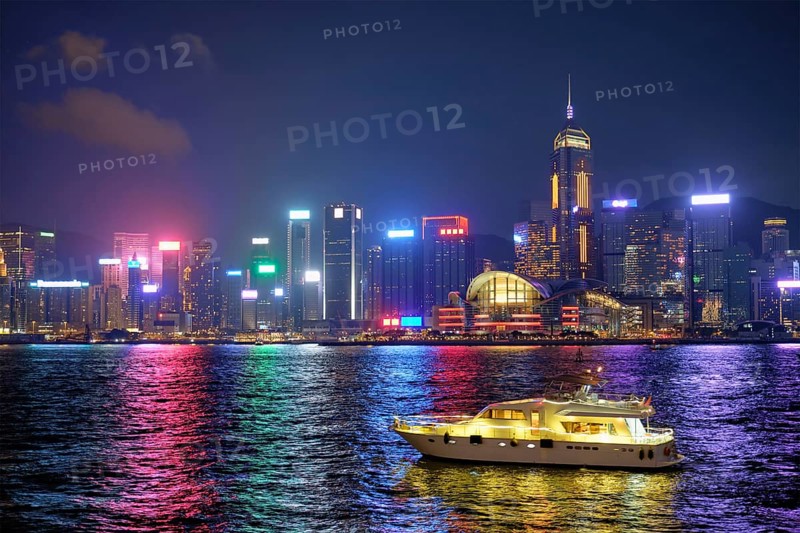 Hong Kong skyline cityscape downtown skyscrapers over Victoria Harbour in the evening illuminated with tourist boat ferries, Hong Kong, China, Asia