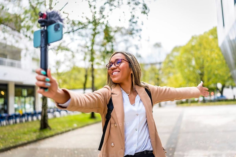 Latin female content creator opening arms showing a city to the audience while recording a video vlog