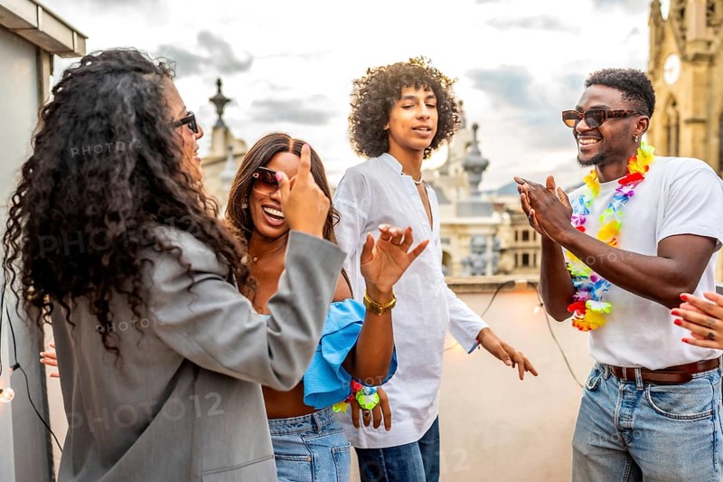 Multi-ethnic young chic friends dancing choreography during rooftop party