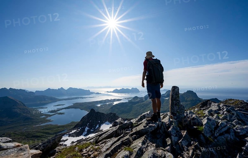 View of mountains and fjord landscape, mountaineer at the summit of Rundfjellet, Sun Star, Austenesfjord fjord, Svolvaer, Nordland, Norway, Europe