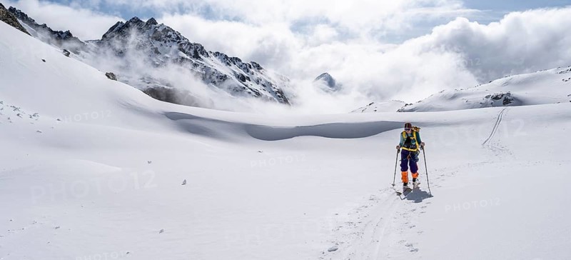Atmospheric clouds in a wintry mountain landscape, ski tourer on the ascent to Porta d'Es-cha, Bündner Haute Route ski tour, Albula Alps, Rhaetian Alps, Grisons, Eastern Switzerland, Switzerland, Europe