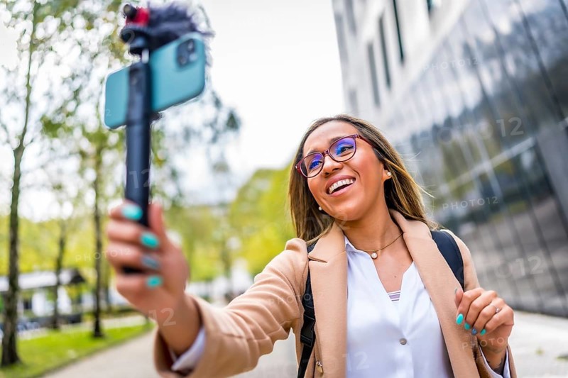 Latin woman vlogger talking to the camera while recording video blog in the city