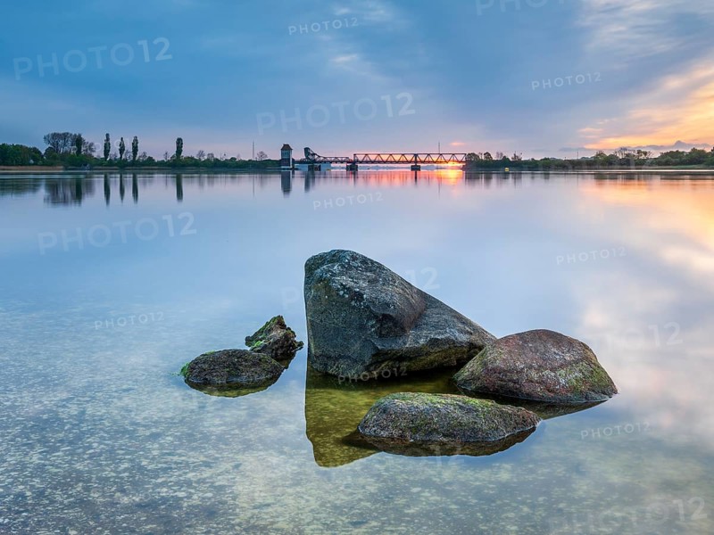 Sunrise at the historic lift bridge of Lindaunis over the Schlei, boulders in the water, Holstein Switzerland, Schleswig-Holstein, Germany, Europe