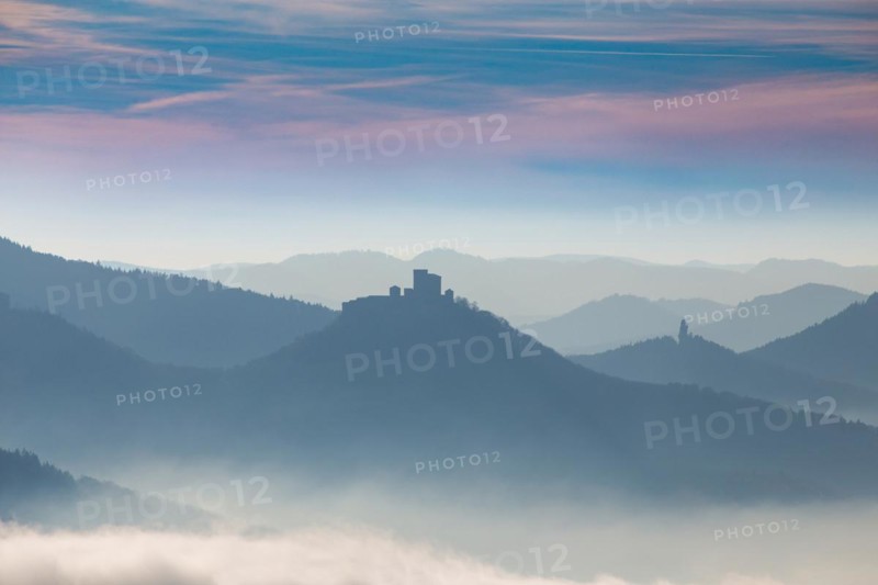 Autumnal panorama of the Palatinate Forest with mountain peaks and valleys in the mist. Trifels Castle near Annweiler can be seen in the centre of the picture