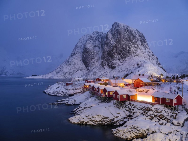 Rorbuer huts of Hamnoy at the fjord at dusk, snowy mountains in the background, Hamnøy, Reine, Moskenesøya, Lofoten, Norway, Europe