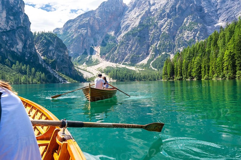 Tourists enjoying a boat trip on the stunning lake braies, surrounded by the breathtaking scenery of the dolomites in summer