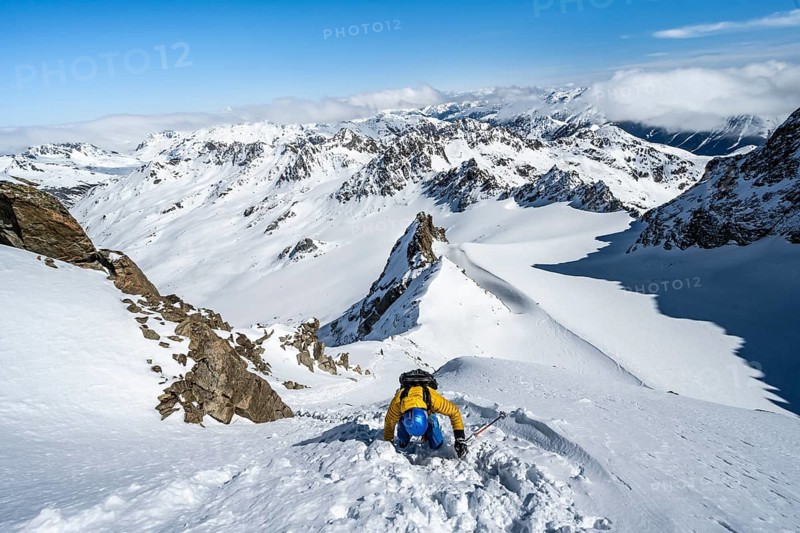 Mountaineer with ice axe and crampons, ascent through steep snowfield to Piz Kesch or Piz d'Es-cha in winter, view of mountain panorama with Vadret da Porchabella glacier, Albula Alps, Rhaetian Alps, Grisons, Eastern Switzerland, Switzerland, Europe