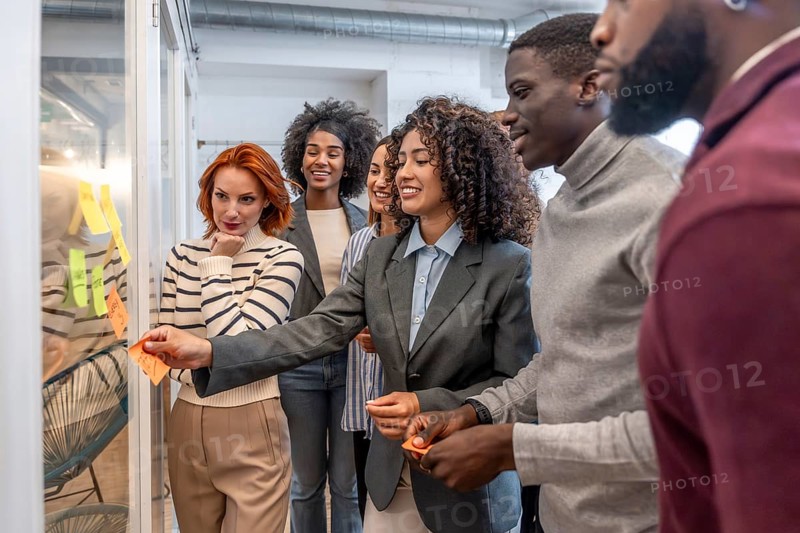 Hispanic woman sticking an adhesive note to a board during brainstorming in a coworking space