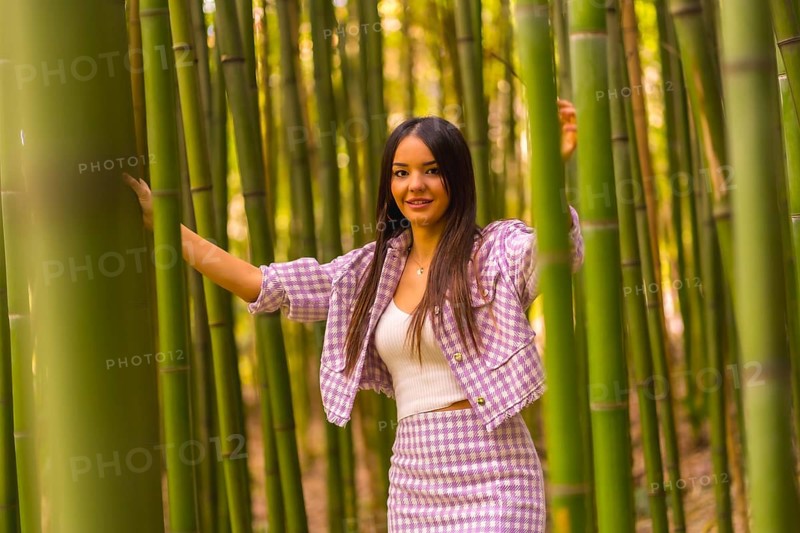 Young caucasian girl with a pink skirt in a bamboo forest. Enjoying the city on summer vacation in a tropical climate, a girl lifestyle walking and smiling in the forest