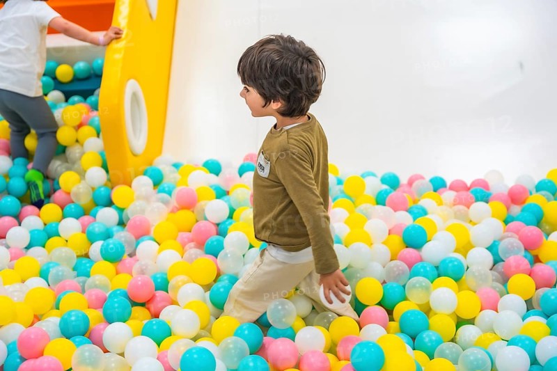 Young boy joyfully playing in a vibrant ball pit, surrounded by a colorful playground that sparks imagination and happiness
