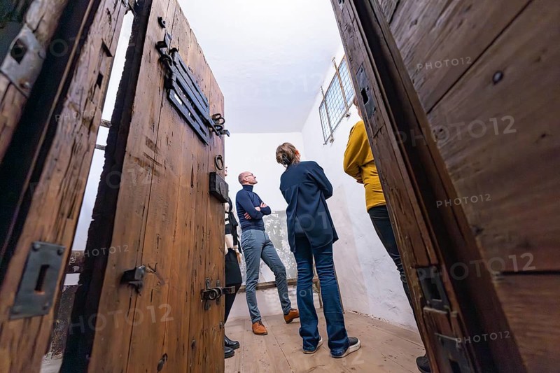 Several people standing in a room with large wooden doors and a historical appearance, Prison Museum, Der Lange, Calw, Black Forest, Germany, Europe