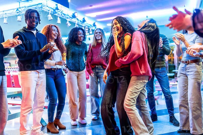Group of young multiethnic friends enjoying a weekend together dancing and having fun in a bowling alley