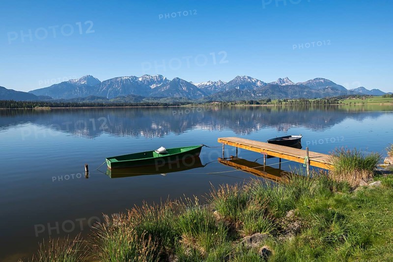 Jetty with green and black boats on a quiet lake in front of a mountain panorama, Hopfen am See, near Füssen, Ostallgäu district, Swabia, Bavaria, Germany, Europe