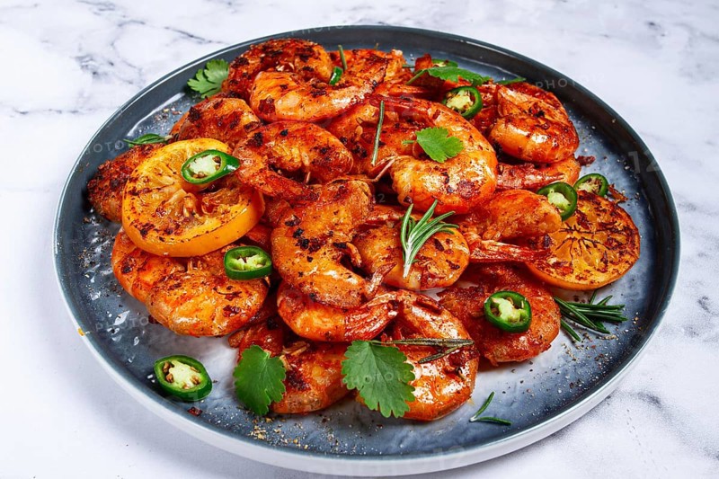 Grilled shrimp, unpeeled, headless, with spices, on a marble table, homemade, no people