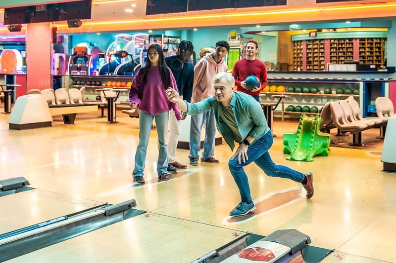 Diverse group of young adults having fun bowling together, enjoying a weekend leisure activity