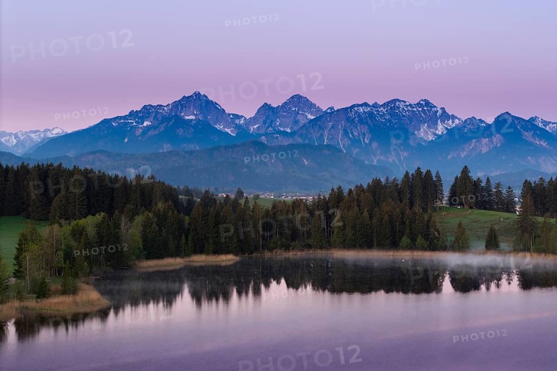 Alpine panorama with a calm lake and mountains in the background in front of sunrise, Hergratsrieder See, Alps, near Füssen, Ostallgäu, Allgäu, Bavaria, Germany, Europe