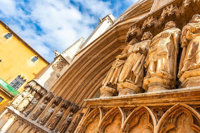 Ancient statues decorating the entrance of tarragona cathedral in spain, showcasing architectural details under a blue sky