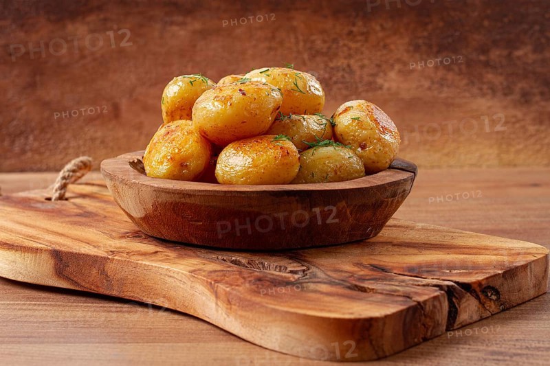 Baked new potatoes, with butter and dill, on a wooden plate, homely, rustic, no people
