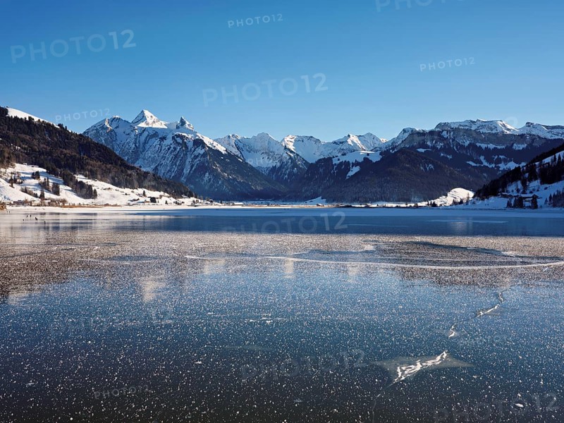 Frozen Sihlsee, reservoir, behind the snow-covered mountains Flübrig and Druesberg, Euthal, Canton Schwyz, Switzerland, Europe