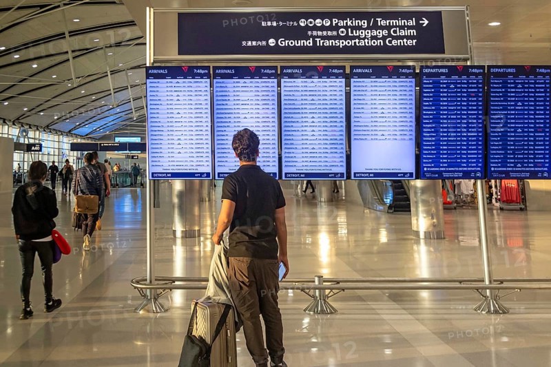Detroit, Michigan - A traveler looks at the arrivals and departures board at Detroit Metro Airport