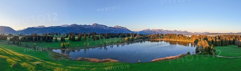 Panoramic view of a lake surrounded by forests and mountains at sunset, Hergratsrieder See, Alps, near Füssen, Ostallgäu, Allgäu, Bavaria, Germany, Europe