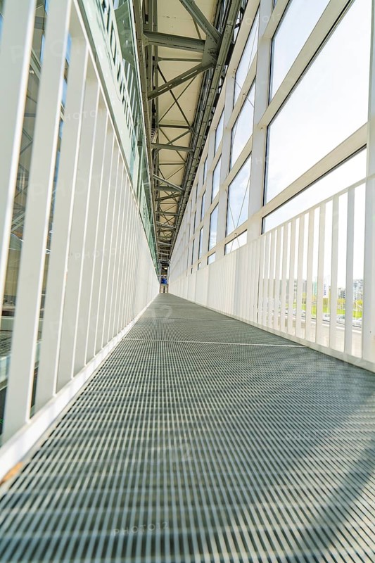 Symmetrical corridor with metal floor and large glass windows, Motorworld Böblingen, Germany, Europe