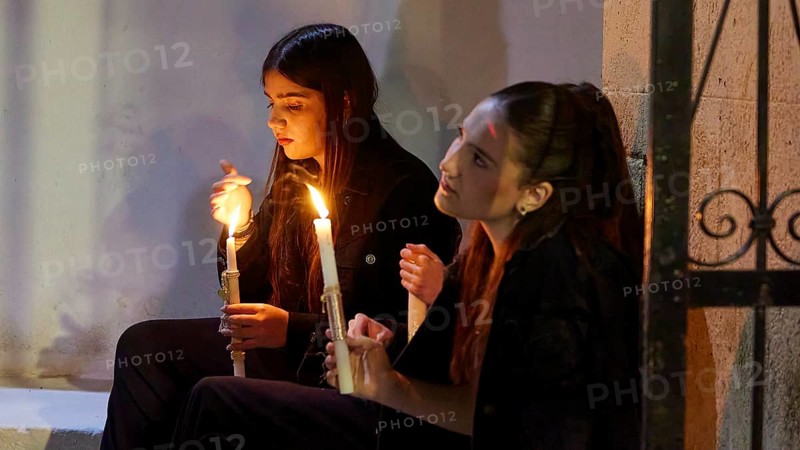 Two girls sit by candlelight, their faces marked by calm and serenity as they quietly contemplate the scene, Holy Light, Easter bonfire Psinthos, Holy Saturday, Easter, Psinthos, Rhodes, Dodecanese, Greek Islands, Greece, Europe