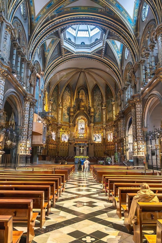 Tourists admiring the interior of santa maria de montserrat basilica, located in the montserrat monastery near barcelona, catalonia, spain