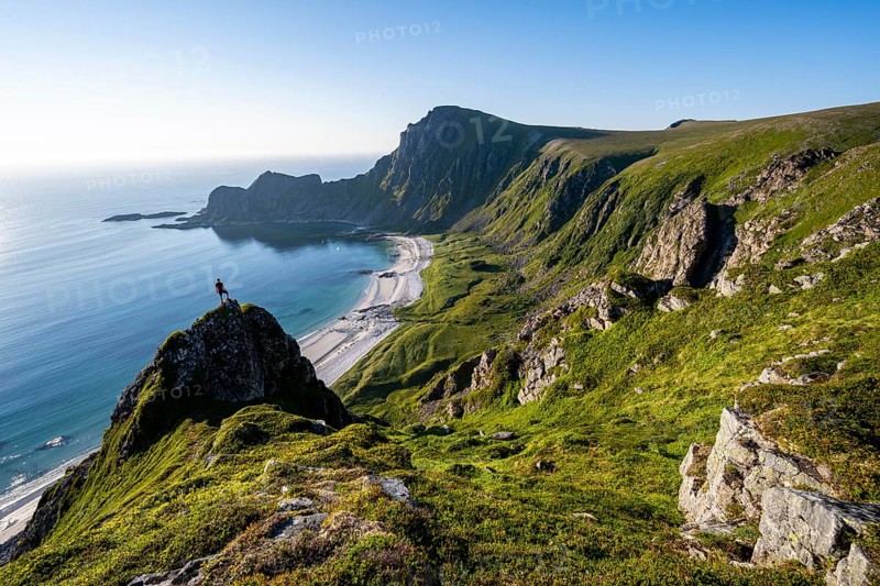 Climber on a rock, view of picturesque coastal landscape, steep coast with peak Måtind or Måtinden, Høyvika beach and sea, hike to the summit of Måtind, Andøya island, Vesterålen, Nordland, Norway, Europe