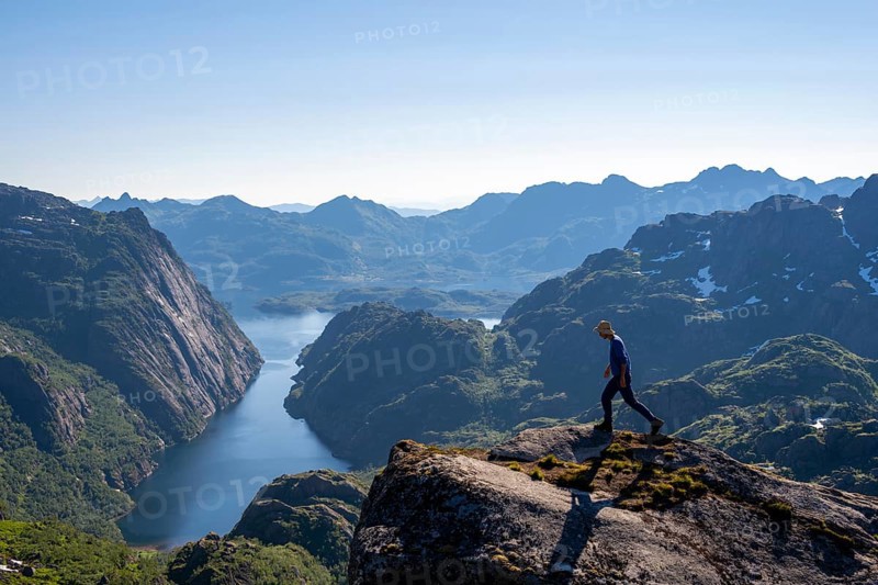 Mountaineer, young man in front of mountain landscape, fjord Trollfjord and mountains, hike to Trollfjord Hytta, at Trollfjord and Raftsund, Lofoten, Nordland, Norway, Europe