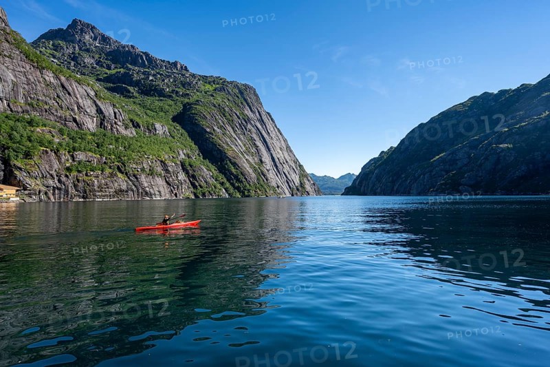 Kayaker with red kayak in the fjord Trollfjord, mountain peaks reflected in the water, fjord landscape and mountains, Lofoten, Nordland, Norway, Europe