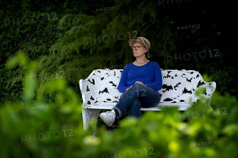 Elderly woman, wearing a sun hat, sitting on a white park bench, pensive, Mainau Island, Constance County, Baden-Württemberg, Germany, Europe