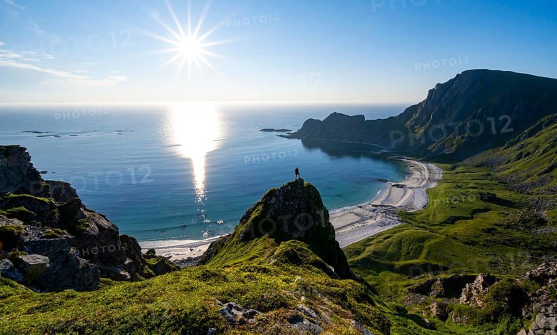Climber on a rock, view of picturesque coastal landscape with sun star, steep coast with peak Måtind or Måtinden, Høyvika beach and sea, hike to the summit of Måtind, Andøya island, Vesterålen, Nordland, Norway, Europe
